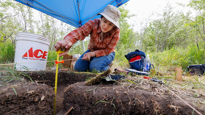 A student works outside under a tent