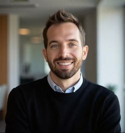Person wearing a black sweater in a bright office setting, face blurred for anonymity.