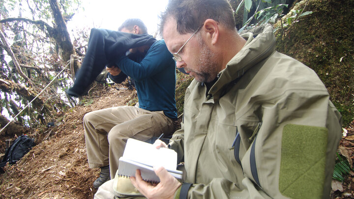 William Belcher looks at a notebook at an excavation site in northeast India.