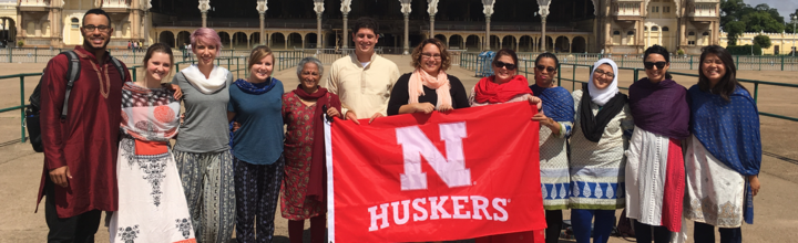 Students and faculty on study abroad trip holding Husker banner